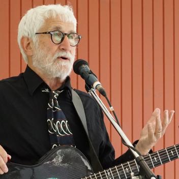 A person with white hair and a guitarAI-generated content may be incorrect.