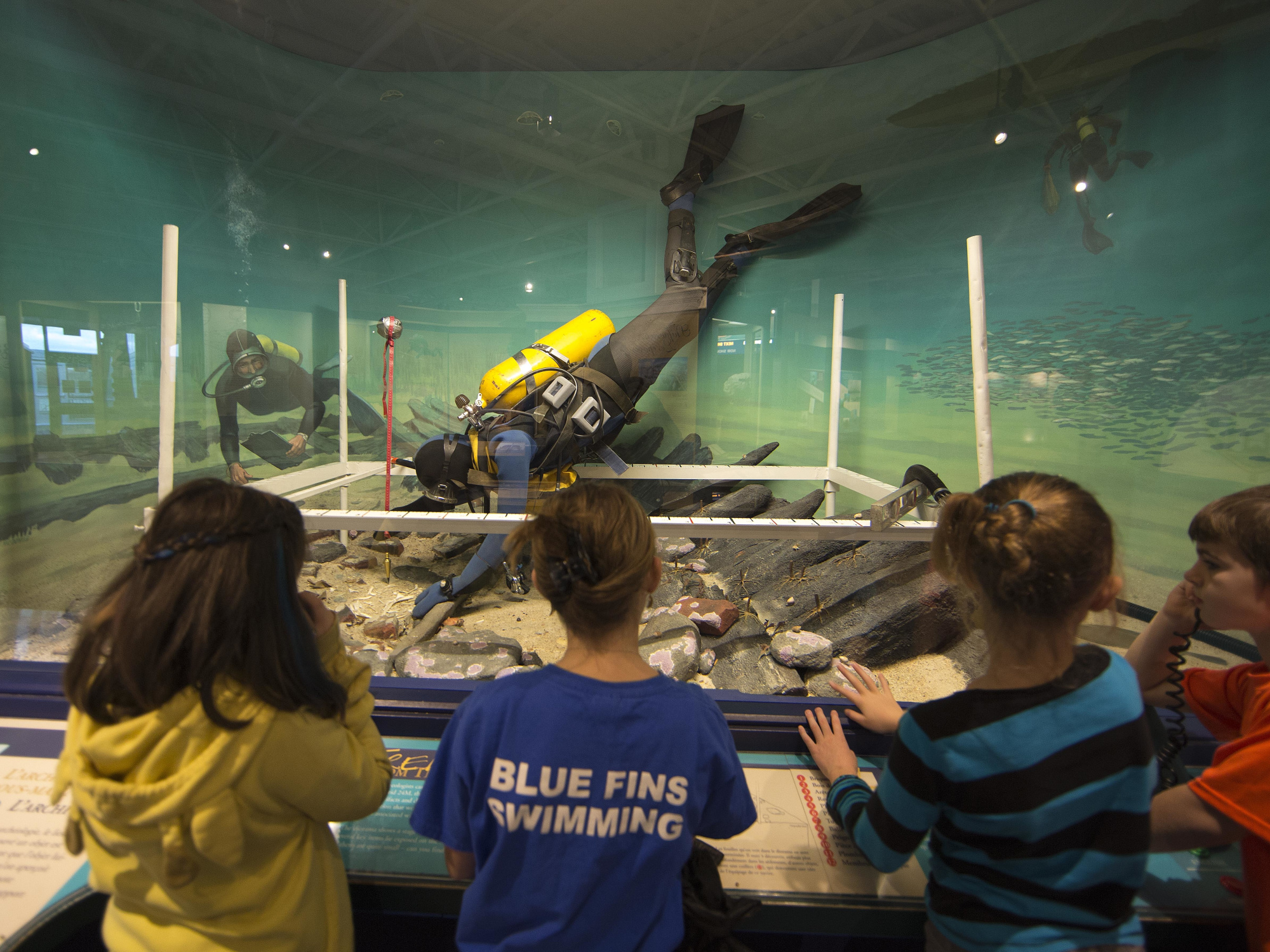 Four children looking at a shipwreck exhibit.