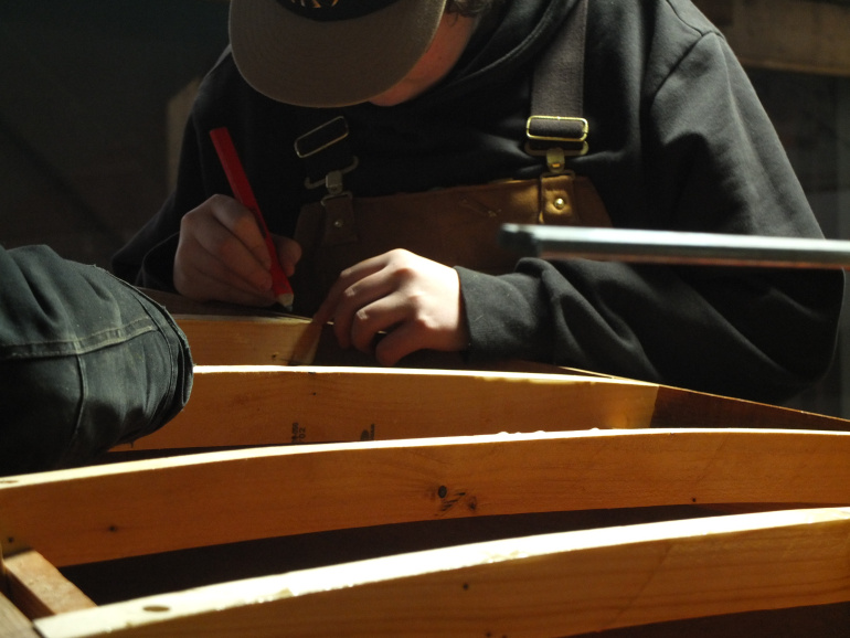 A student building the frame of a boat in the boat shed at the Maritime Museum of the Atlantic.