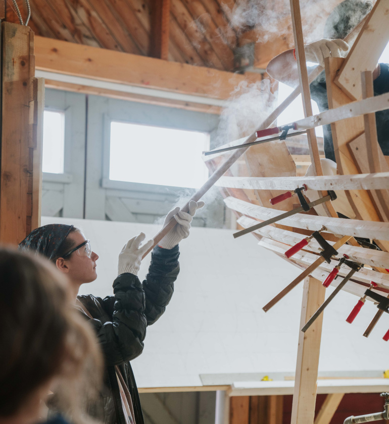 Students steam bending a wood boat from in the boat shed at the Maritime Museum of the Atlantic.