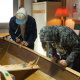 Students using hand tools to build a boat in the boat shed at the Maritime Museum of the Atlantic.
