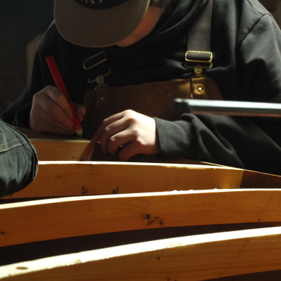 A student building the frame of a boat in the boat shed at the Maritime Museum of the Atlantic.