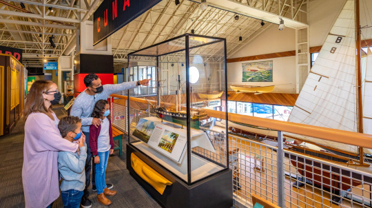 Masked family looking at model ships in the Age of Steam gallery 